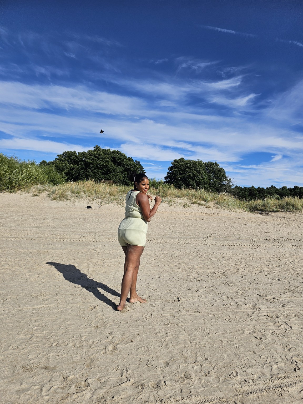 Jade looking back while walking forward across a bright beach
